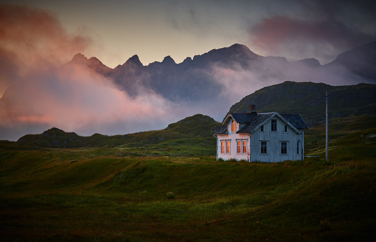 Remote cabin near a mountain under clouds
